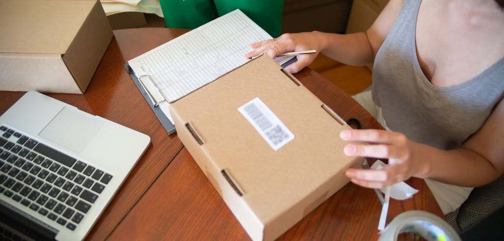 A women labeling a box with a barcode.